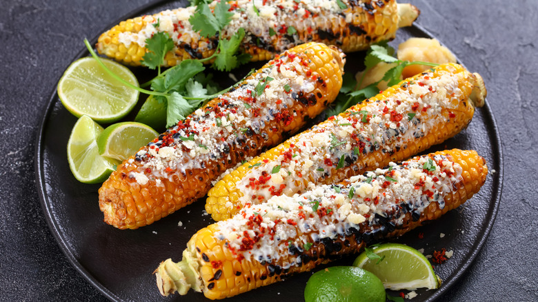 Grilled Mexican street corn on plate with limes