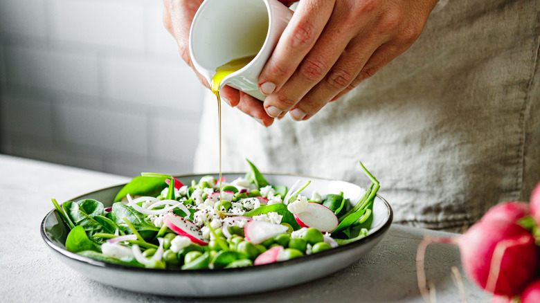 Person pouring dressing over a plate of salad