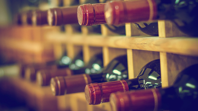 Red wine bottles lying down on wooden racks
