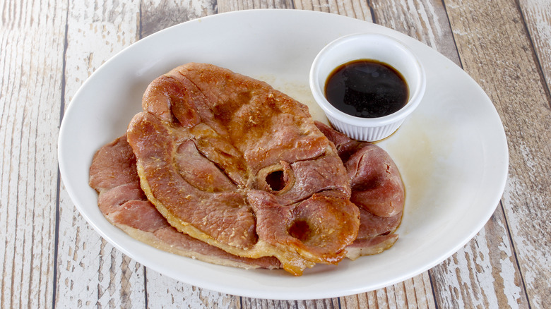 Two slices of country ham with red-eye gravy in cup on the side