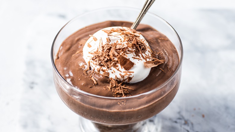 Chocolate mousse in a glass dish with dollop of whipped cream and chocolate shavings