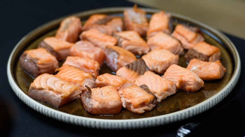 Fried salmon small pieces. slices, cubes. Closeup on a ceramic plate