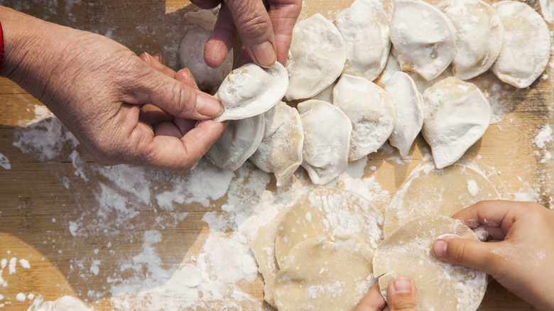 Two people folding potstickers