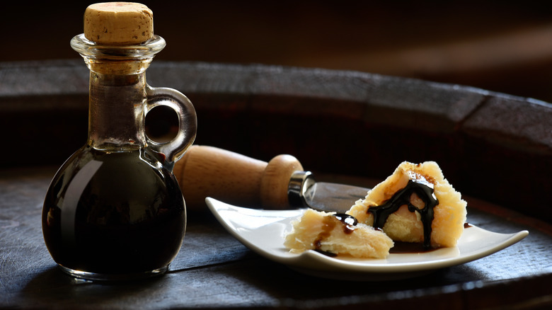 A bottle of balsamic next to block of parmesan 