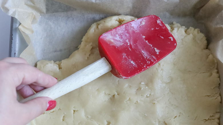 spatula pressing crust into dish