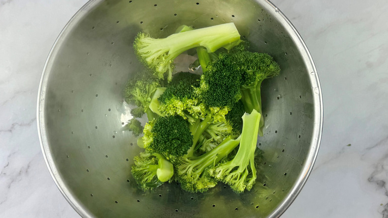 cooked broccoli draining in colander