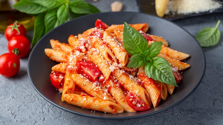 A bowl of penne with tomato and basil