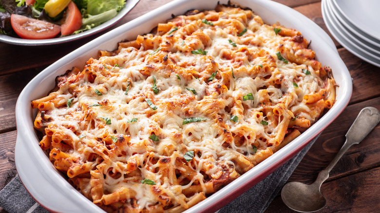 Baked ziti in a casserole dish on a wooden table